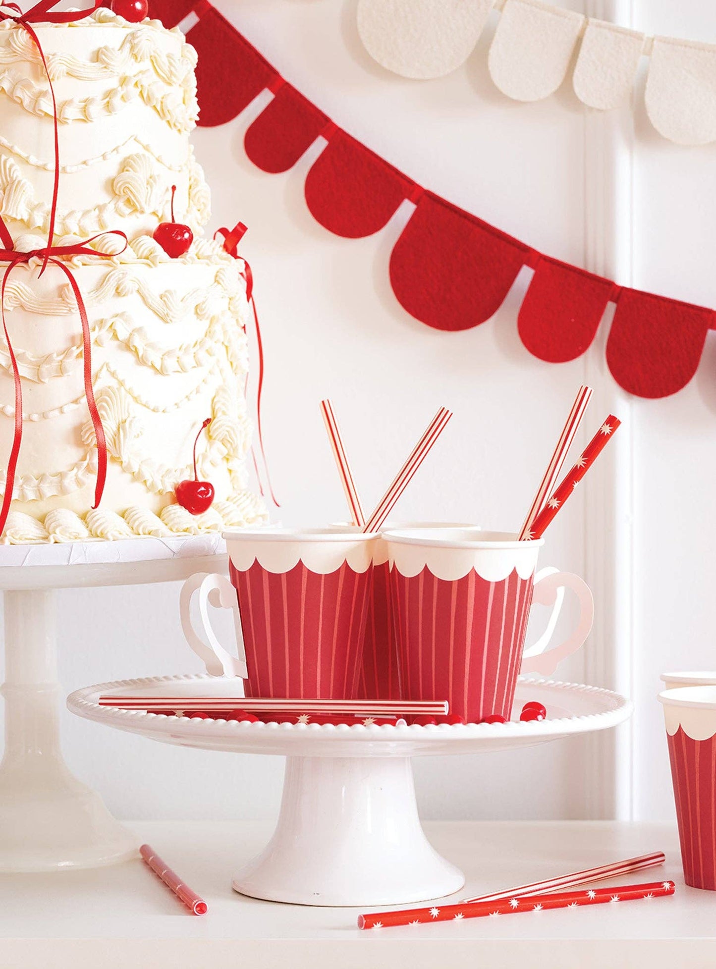 Red and white party setup with cake, straws, and decorative banner.