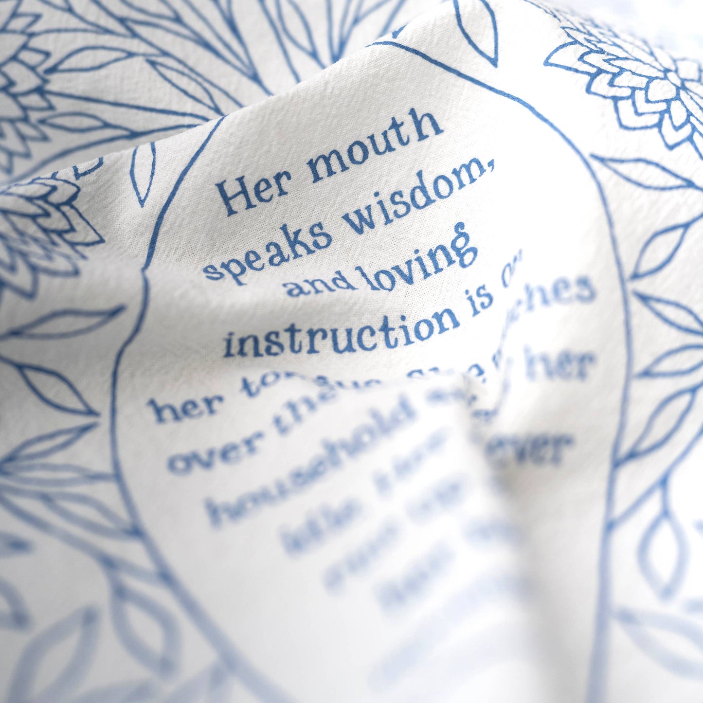 Close-up of delicate hand-lettered verse from Proverbs 31 on soft white cotton fabric