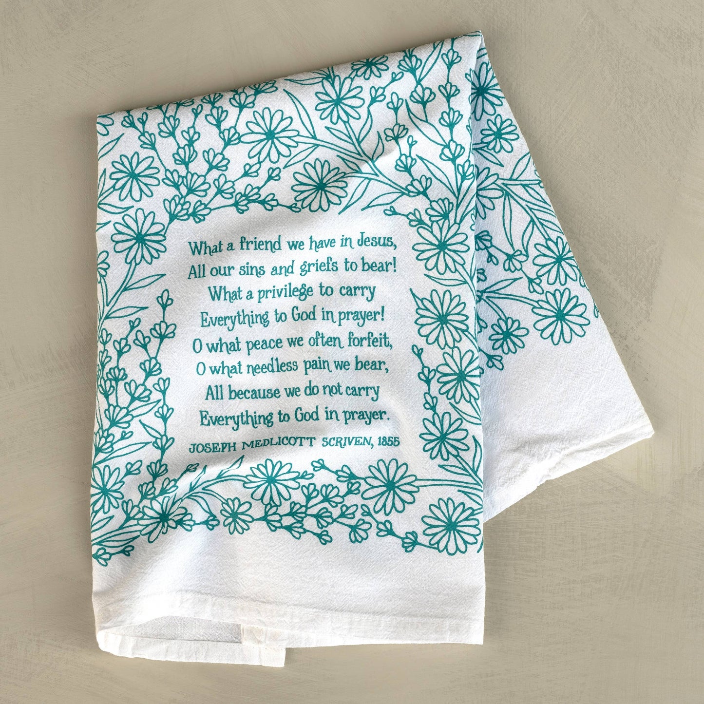 Flat lay of “What a Friend We Have in Jesus” turquoise hymn tea towel with floral artwork