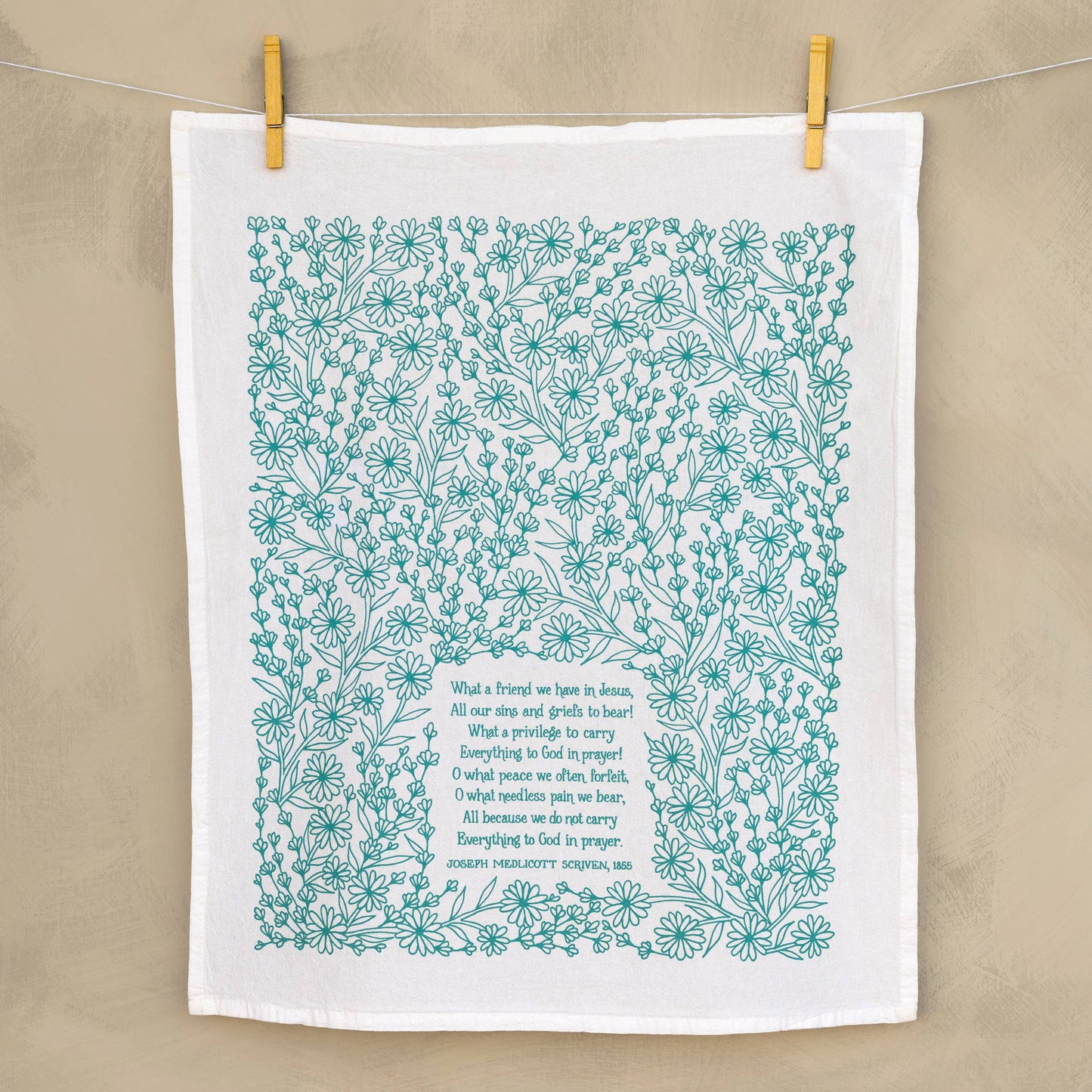 Turquoise hymn tea towel hung as wall decor in cozy, peaceful home setting