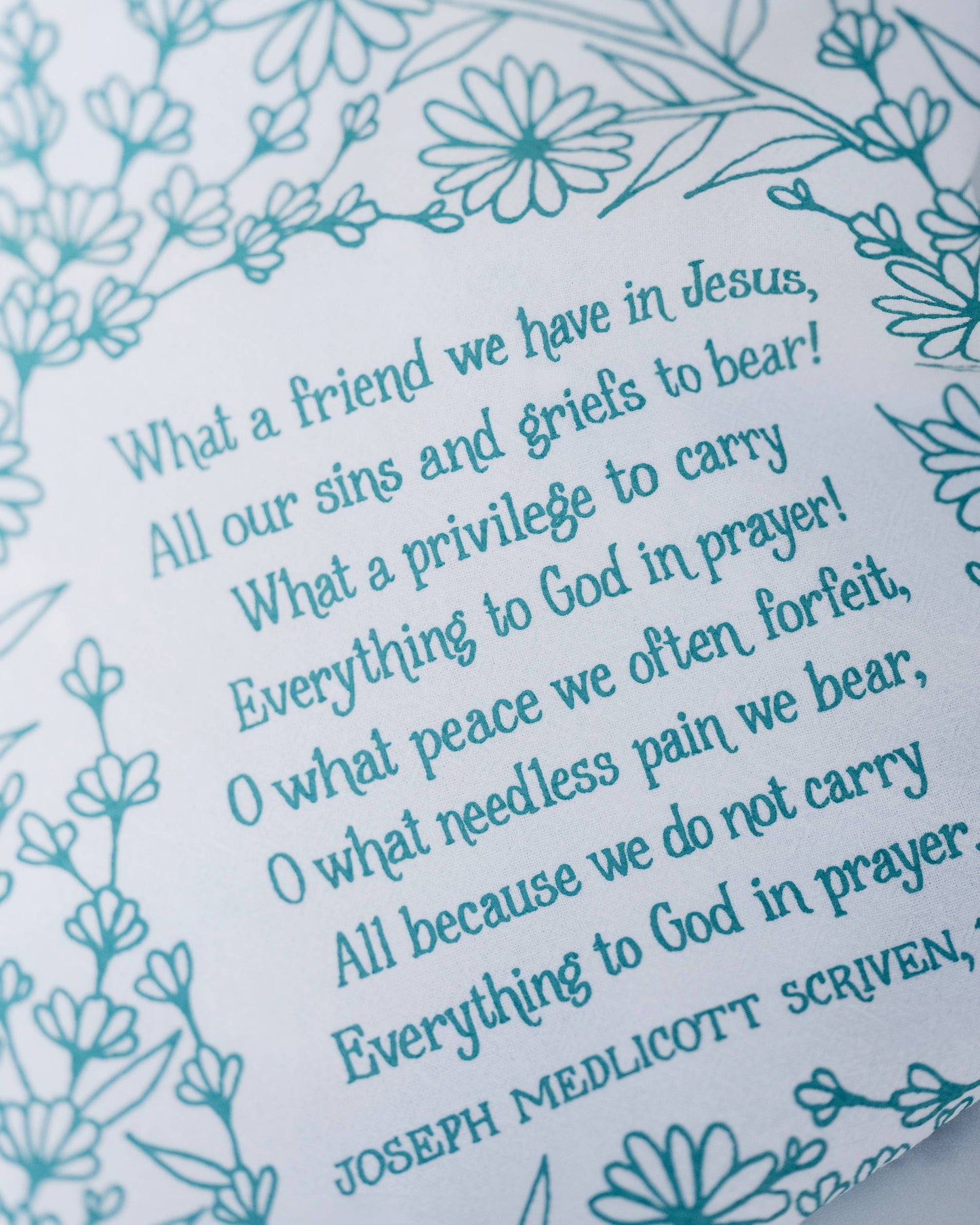 Close-up of hymn lyrics printed on white cotton with detailed floral design